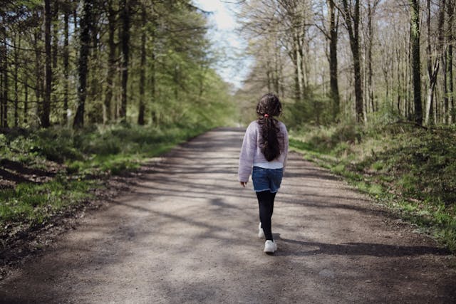 A peaceful scene of a girl walking through a serene forest.